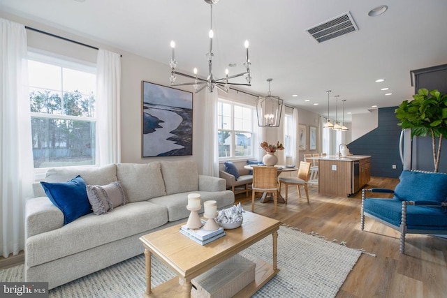 living room with an inviting chandelier, sink, and light hardwood / wood-style floors