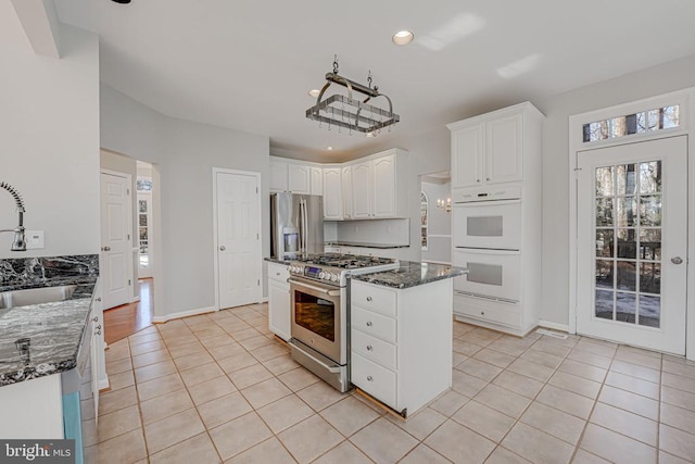 kitchen featuring light tile patterned flooring, white cabinetry, sink, dark stone countertops, and stainless steel appliances