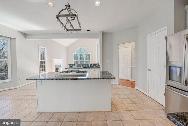 kitchen featuring pendant lighting, stainless steel fridge with ice dispenser, light tile patterned floors, and dark stone countertops