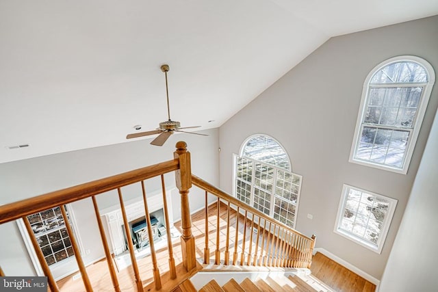 stairs with hardwood / wood-style floors, high vaulted ceiling, and ceiling fan