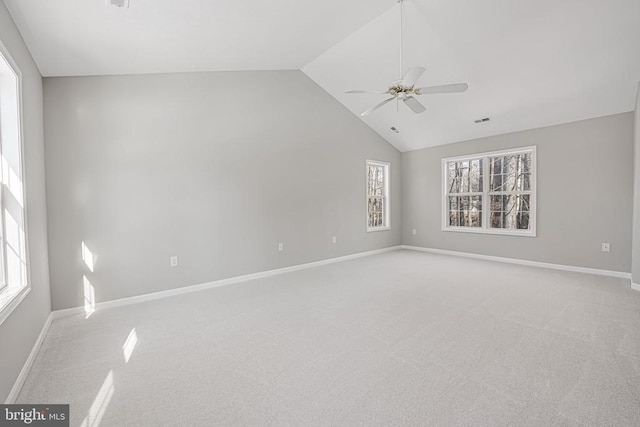 empty room with lofted ceiling, a wealth of natural light, light colored carpet, and ceiling fan