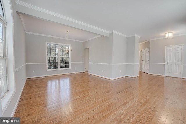 spare room with crown molding, a notable chandelier, and light wood-type flooring