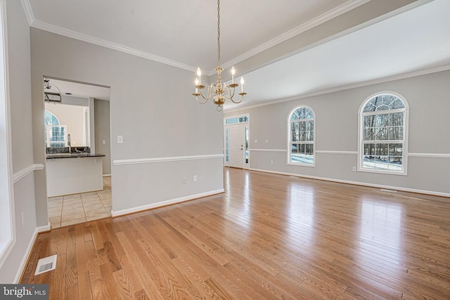 unfurnished room with crown molding, a chandelier, and light hardwood / wood-style flooring