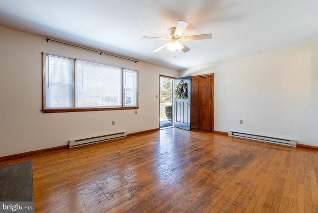 empty room with hardwood / wood-style flooring, ceiling fan, and a baseboard heating unit