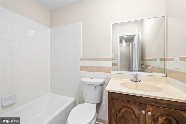 bathroom featuring vanity, tile walls, and toilet