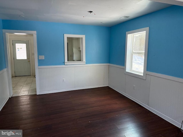 unfurnished room with dark wood-type flooring and a wealth of natural light