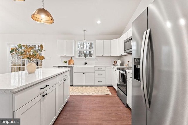 kitchen featuring white cabinetry, stainless steel appliances, sink, and hanging light fixtures