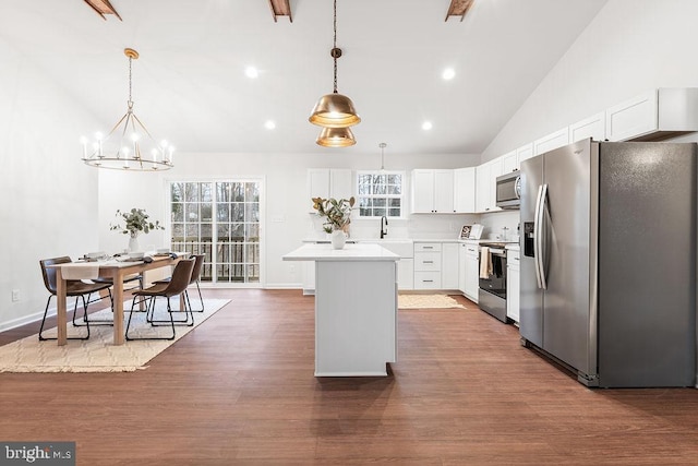 kitchen featuring stainless steel appliances, a center island, white cabinets, and decorative light fixtures