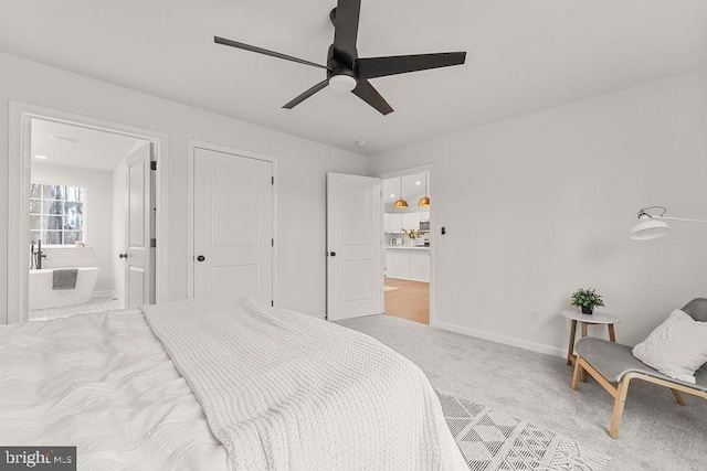 bedroom featuring ensuite bath, light colored carpet, and ceiling fan