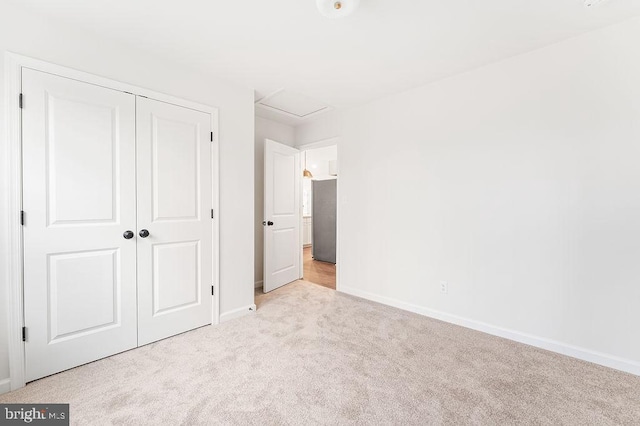 unfurnished bedroom with light colored carpet, a closet, and stainless steel refrigerator