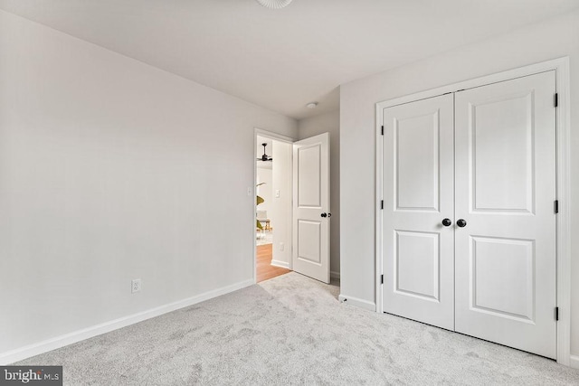 unfurnished bedroom featuring light colored carpet and a closet