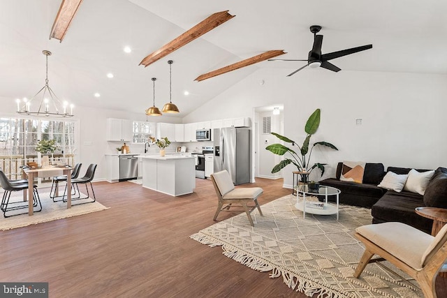 living room with ceiling fan with notable chandelier, high vaulted ceiling, sink, hardwood / wood-style flooring, and beam ceiling