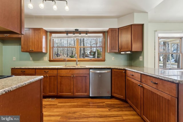 kitchen with dishwasher, sink, light stone counters, and light wood-type flooring