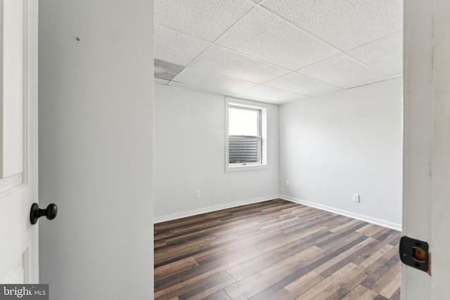 spare room with dark wood-type flooring and a paneled ceiling