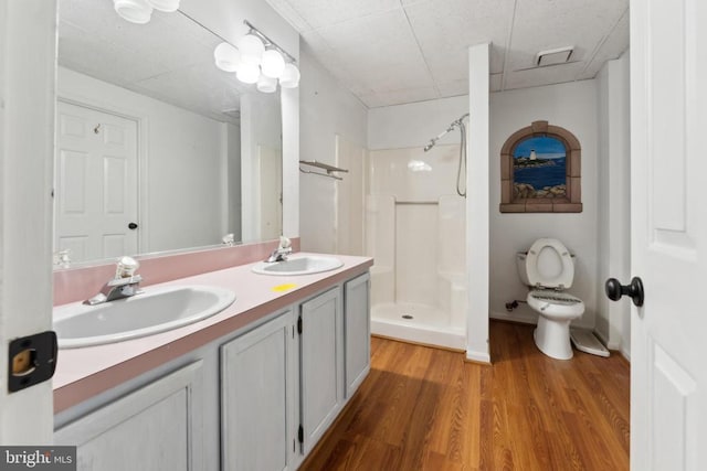 bathroom with wood-type flooring, toilet, vanity, and walk in shower