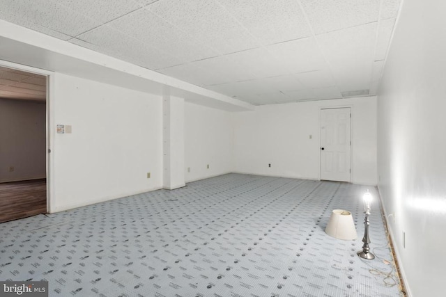 spare room featuring light colored carpet and a paneled ceiling