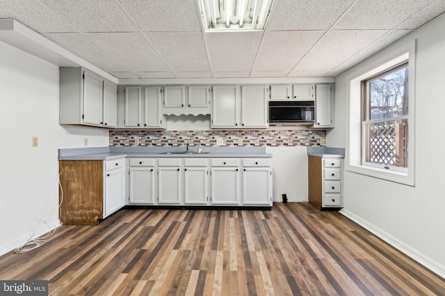 kitchen featuring a paneled ceiling, tasteful backsplash, sink, gray cabinetry, and dark hardwood / wood-style flooring