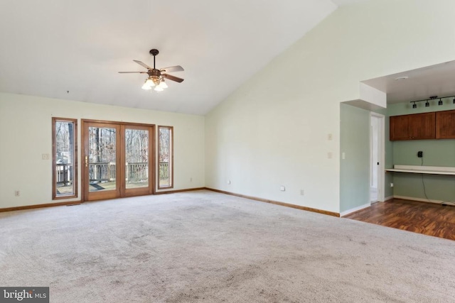 unfurnished living room featuring ceiling fan, track lighting, high vaulted ceiling, and dark colored carpet