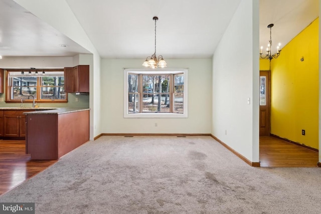 kitchen with vaulted ceiling, a healthy amount of sunlight, an inviting chandelier, and decorative light fixtures