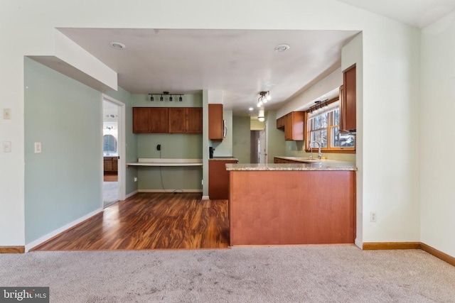 kitchen with sink, rail lighting, kitchen peninsula, and dark colored carpet