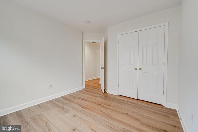 unfurnished bedroom with a closet and light wood-type flooring