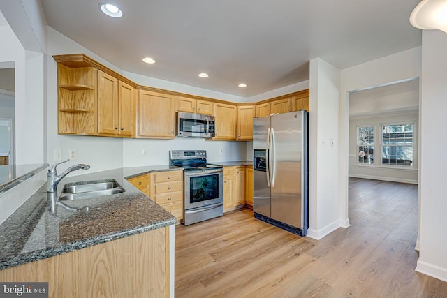 kitchen with light wood-type flooring, stainless steel appliances, sink, and dark stone countertops