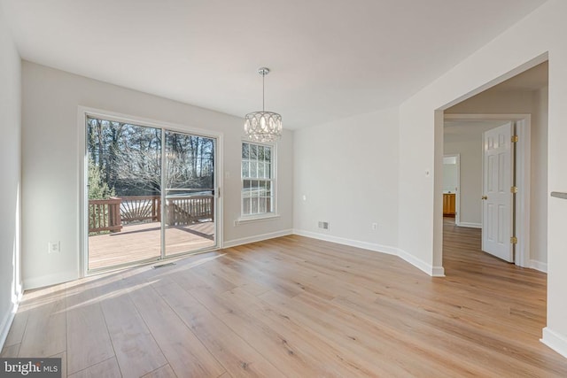 unfurnished dining area featuring a chandelier and light wood-type flooring