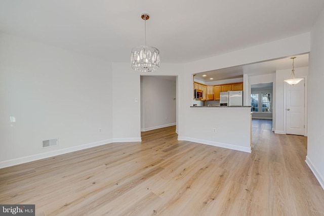 unfurnished living room featuring light hardwood / wood-style flooring and a notable chandelier