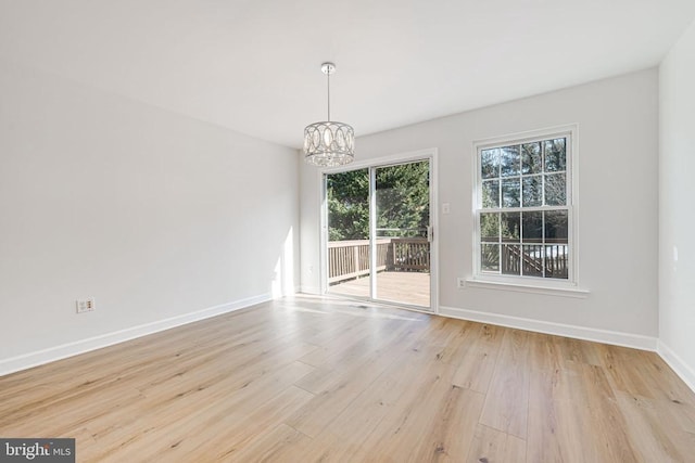 unfurnished dining area featuring a notable chandelier and light hardwood / wood-style floors