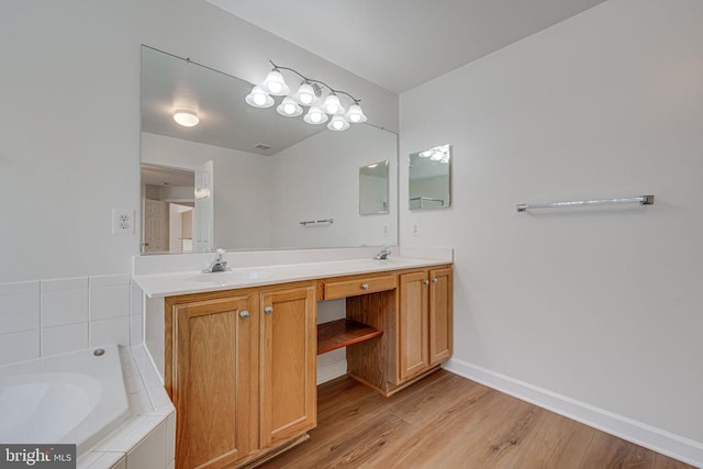 bathroom with vanity, tiled tub, and wood-type flooring