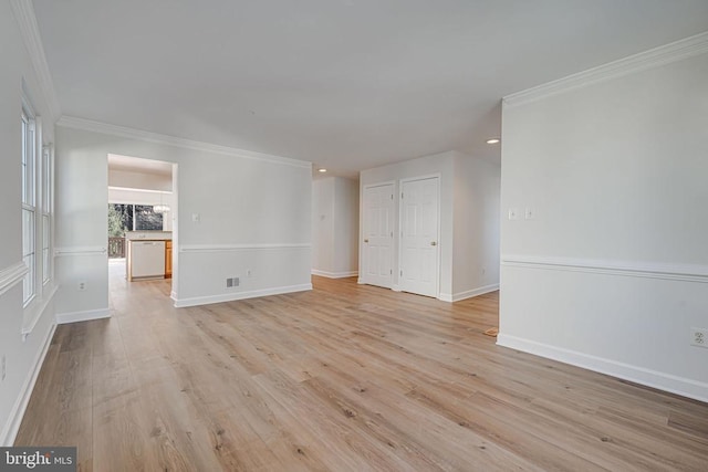 empty room with crown molding and light hardwood / wood-style flooring