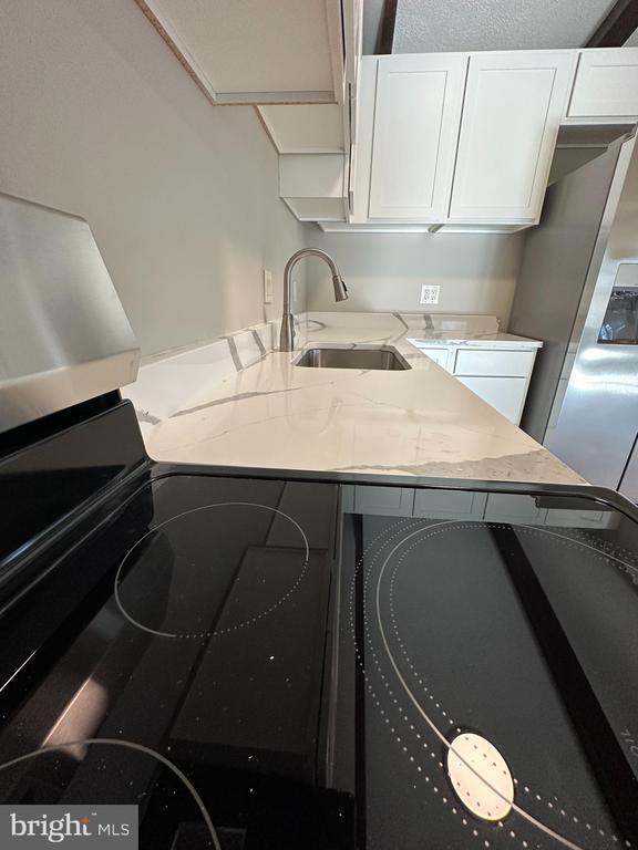 kitchen featuring white cabinetry, light stone countertops, and sink