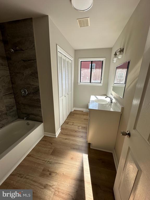 bathroom featuring vanity, hardwood / wood-style flooring, and tiled shower / bath combo