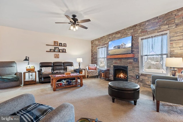 living room featuring carpet, a stone fireplace, and ceiling fan