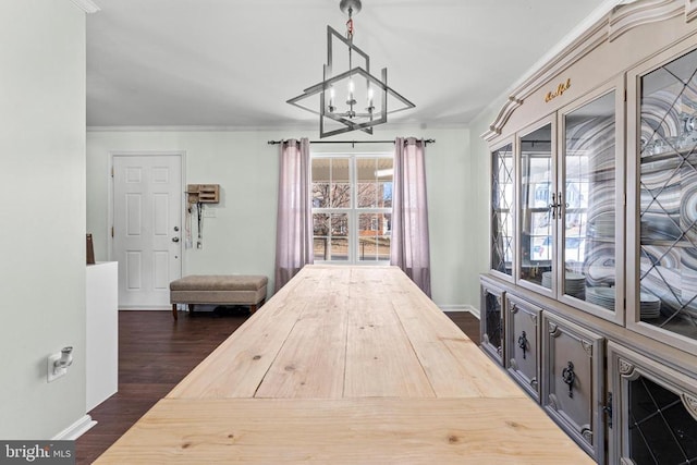 unfurnished dining area featuring a notable chandelier, dark wood-type flooring, and ornamental molding