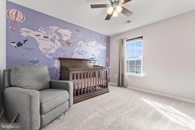 bedroom with a crib, light colored carpet, and ceiling fan