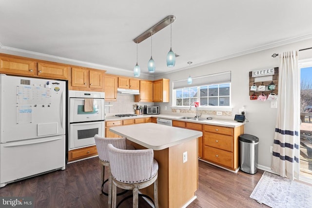 kitchen with a kitchen island, decorative light fixtures, sink, dark hardwood / wood-style flooring, and white appliances