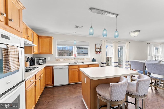 kitchen featuring decorative light fixtures, sink, dark hardwood / wood-style flooring, crown molding, and white appliances