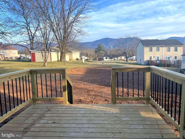 wooden terrace featuring an outbuilding, a residential view, a mountain view, and a yard