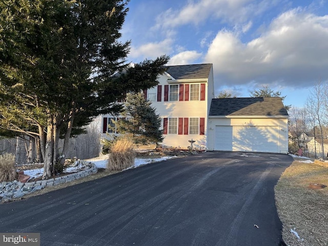 colonial inspired home with an attached garage and aphalt driveway