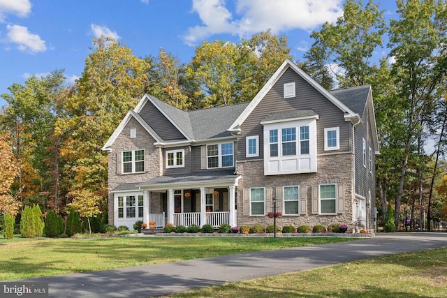 view of front of home featuring stone siding, a porch, and a front lawn