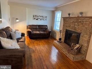 living area featuring crown molding, a fireplace with raised hearth, and wood finished floors