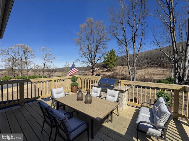 deck featuring outdoor dining space and a grill