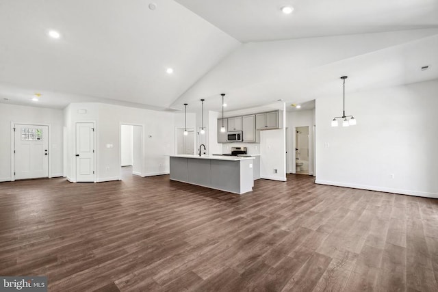 unfurnished living room with dark wood finished floors, a sink, baseboards, and an inviting chandelier