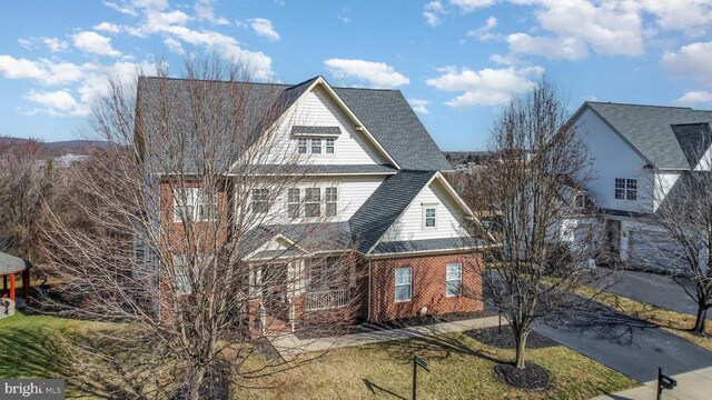 shingle-style home with brick siding and a front yard