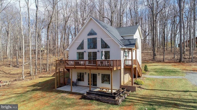 back of house with a shingled roof, a deck, a patio, and a yard