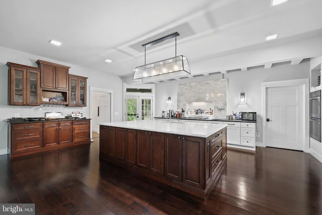 kitchen with glass insert cabinets, dark wood-type flooring, decorative light fixtures, french doors, and a sink