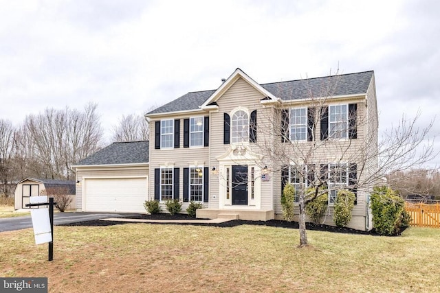 colonial inspired home featuring driveway, a shingled roof, an attached garage, fence, and a front yard