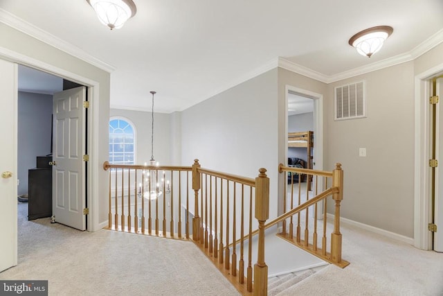 hallway featuring carpet floors, ornamental molding, an upstairs landing, and visible vents