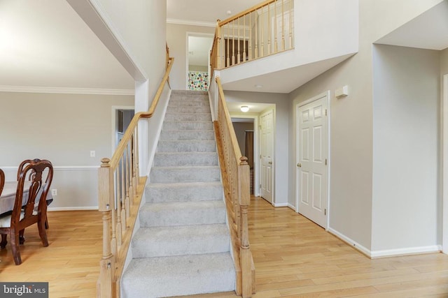 staircase featuring crown molding, baseboards, and wood finished floors